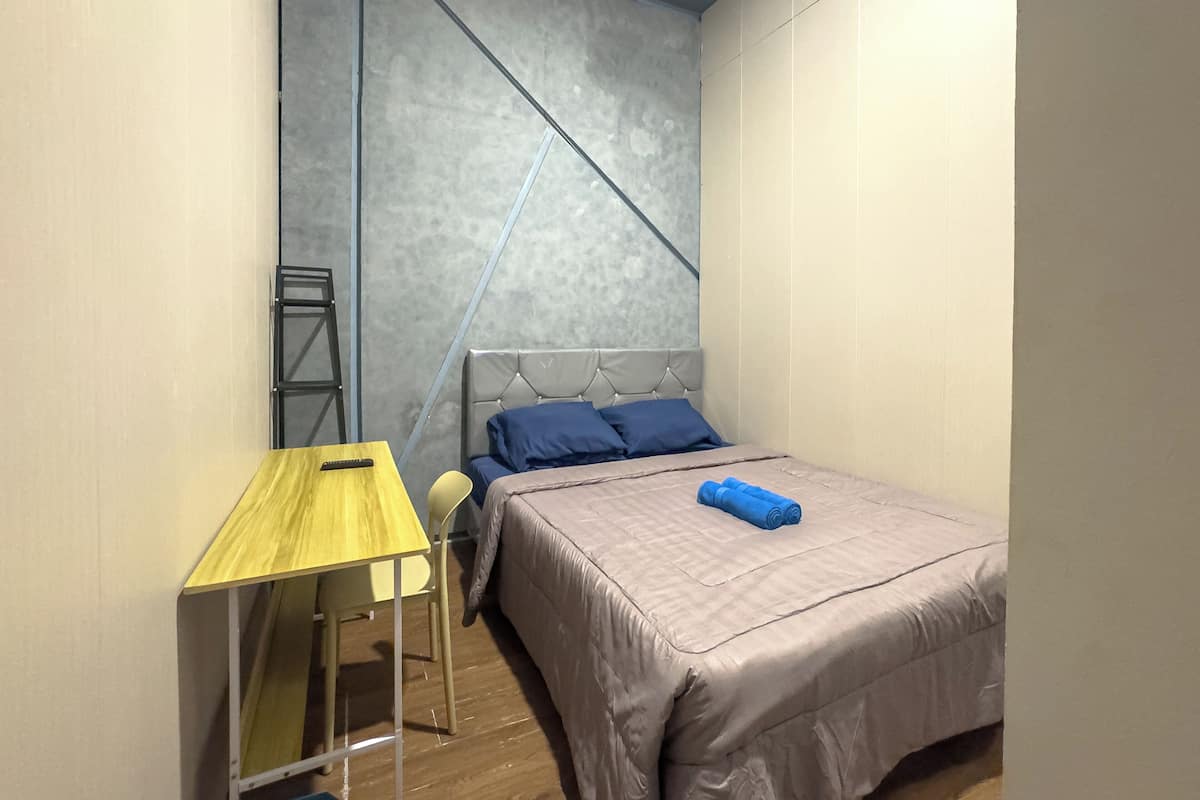 A bedroom with a bed, a small table, a chair, and a ladder against the wall.