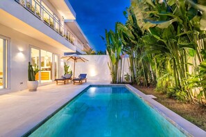 A modern pool area with a clear pool, two lounge chairs, and a potted plant. - Eleven Villa Canggu (Canggu)