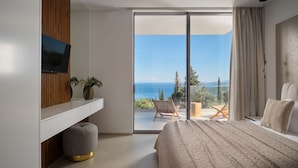 A modern bedroom with a large bed, a TV, a plant, and a view of the sea. - Doci Kelios Villa with heated pool (Zakynthos)