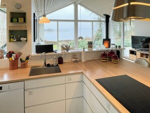 Une cuisine moderne dotée d’une grande fenêtre, d’un évier, d’une cuisinière et d’un téléviseur.