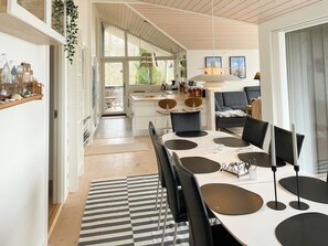A modern kitchen with a dining area, large windows, and a view of the outdoors. - Stunning sunrises over Harre Vig (Roslev)