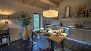Eine moderne Küche mit Essbereich, inklusive großem Tisch, Stühlen, einer Pendelleuchte und einem Blumentopf.