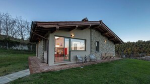 Ein Steinhaus mit Terrasse, Glastür und Gartenmöbeln.