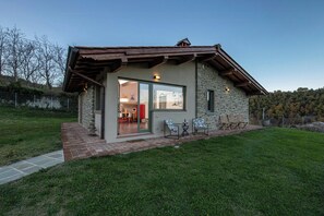 Ein Steinhaus mit Terrasse, Glastür und Gartenmöbeln.