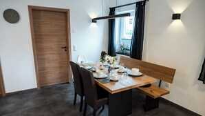Un'area pranzo con un tavolo di legno apparecchiato per due, una panca e una finestra con tende.