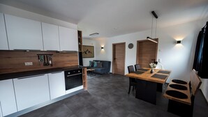 Una cucina moderna con mobili bianchi, un piano di lavoro in legno e un'area pranzo con tavolo e sedie.