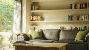 Un accogliente soggiorno con soffitto in legno, un divano, un tavolino da caffè e librerie piene di libri.