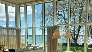 Una sala de estar moderna con un ventanal grande, un sofá, una mesa de comedor y vistas al mar.