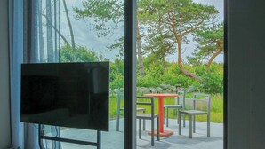 Ein modernes Zimmer mit großem Fenster, Flachbildfernseher und einem kleinen Tisch mit Stühlen.