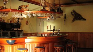 Una zona de bar con mostrador de madera, taburetes y un estante con figuras decorativas de animales.