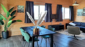 Una habitación con paneles de madera, una mesa de comedor, sillas, un sofá y un televisor.