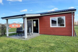 A small red building with a covered patio area and a single window.