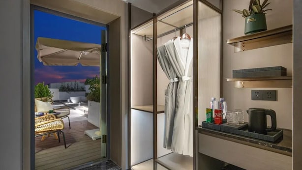 Un baño moderno con cabina de ducha de vidrio, un perchero y un estante con artículos de aseo.