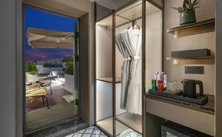 A modern bathroom with a glass shower enclosure, a towel rack, and a shelf with toiletries.. Yinzhuo Hotel