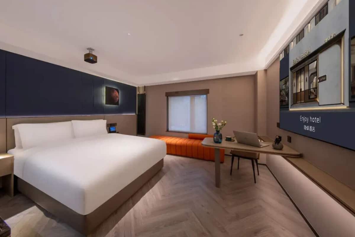 A modern hotel room with a large bed, a desk, and a seating area.