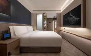 A modern hotel room with a large bed, a bedside control panel, a TV mounted on the wall, and a door leading to a bathroom. - Yinzhuo Hotel (Beijing)