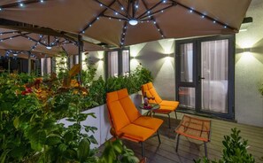 An outdoor patio with a covered seating area, a table, and potted plants. - Yinzhuo Hotel (Beijing)