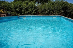 A clear blue swimming pool surrounded by dense green foliage. - Country Holiday home with shared pool (Someren-Heide)