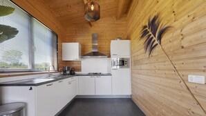 Una cocina moderna con armarios blancos, una campana de acero inoxidable y un horno empotrado.
