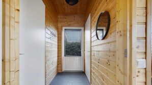 Un pasillo con paredes de madera, una puerta blanca y una ventana con persianas.