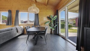 Un interior de madera con una mesa de comedor, sillas, un sofá y un ventanal grande.