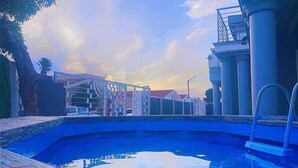 A swimming pool with a view of a building with columns and a bridge in the background. - Quaaamiii Accomodation (Cape Town)