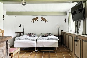 A room with a bed, a desk, a chair, a lamp, and a TV mounted on the wall. - Unique summer house with seaweed roof on Læsø (Læsø)