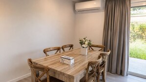 Spiseområde med et træbord, seks stole, en vase med blomster og en aircondition.
