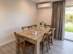 A dining area with a wooden table, six chairs, a vase with flowers, and an air conditioning unit. - No. 19 3B Pimpama Home (Pimpama)