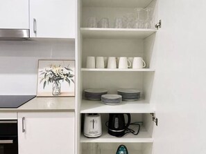 A kitchen with white cabinets, a toaster, a kettle, and a coffee maker on the countertop.