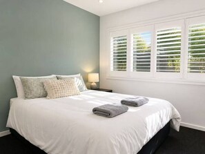 A neatly made bed with white bedding, two pillows, and two folded towels. - No.21 3B Pimpama Home (Pimpama)