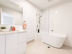 A modern bathroom with a freestanding bathtub, a sink with a mirror, and a potted plant. - No.21 3B Pimpama Home (Pimpama)