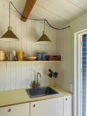A kitchen with a sink, two pendant lights, a vase with flowers, and a shelf with various items. - Summer house near Ahl Beach and Ebeltoft (Ebeltoft)