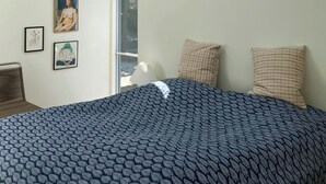 Ein Schlafzimmer mit Oberlicht, einem Bett mit gemusterten Bettbezügen und zwei Kissen.