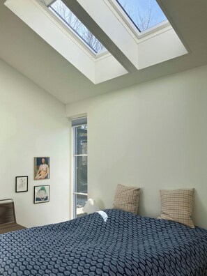A bedroom with a skylight, a bed with patterned bedding, and two pillows. - Natural light and short walk to water in home (Vordingborg)