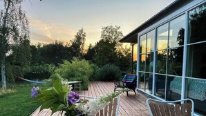 Eine Holzterrasse mit Tisch, Stühlen und einem Blumenvasen.