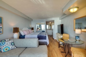 Ein Hotelzimmer mit Bett, Sofa, Glastisch, Fernseher und Spiegel.