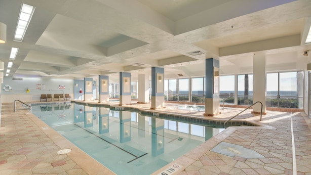 Una piscina interior con señalización clara, suelo de baldosas y vistas al océano a través de amplias ventanas.