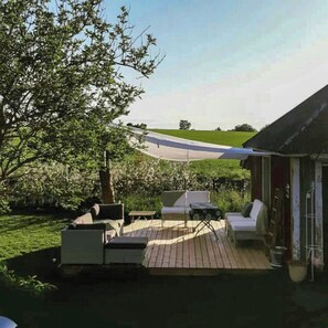 Eine Terrasse mit Sitzgelegenheit, ein Baum und Blick auf eine Straße.