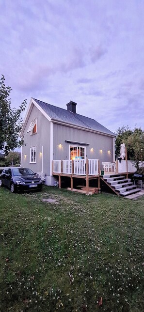 Einbungalow mit Veranda, ein Auto vor der Einfahrt und eine Statue im Hintergrund.