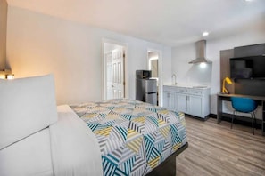 A bedroom with a bed, a desk, a chair, a television, a microwave, and a sink. - 1 King Bed | Non-Smoking, Kitchen (Eureka)