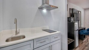 A modern kitchen with a stainless steel sink, a built-in range hood, and a compact refrigerator. - 1 King Bed | Non-Smoking, Kitchen (Eureka)