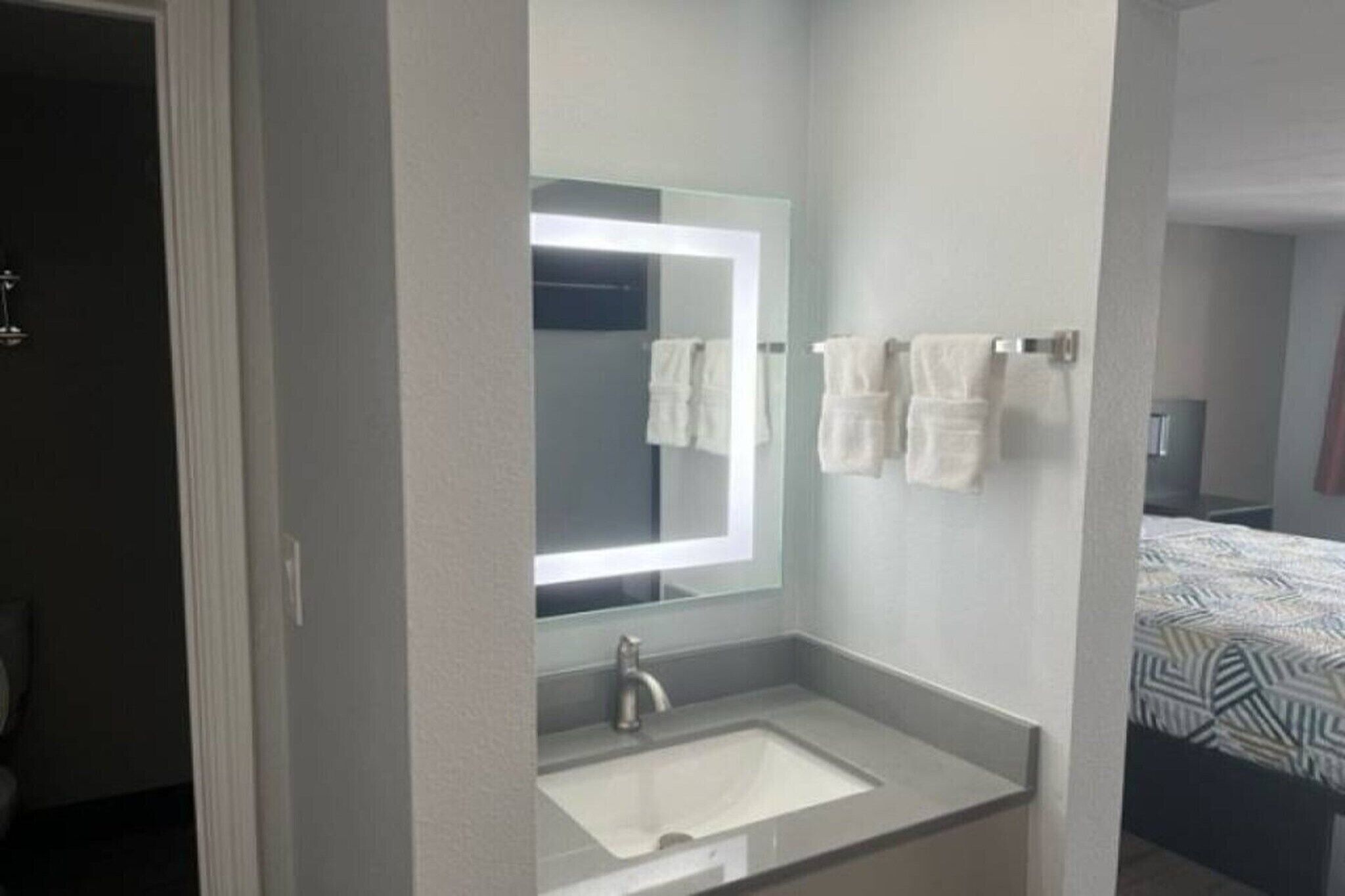 A bathroom with a mirror, sink, and towel rack.