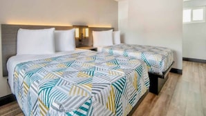 Habitación de hotel con dos camas, una mesita de noche y lámparas de pared.