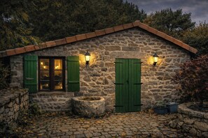 A stone cottage with a tiled roof, a window with shutters, and two wall-mounted lights. - Cottage in former bakery in Dordogne (Saint-Estèphe)