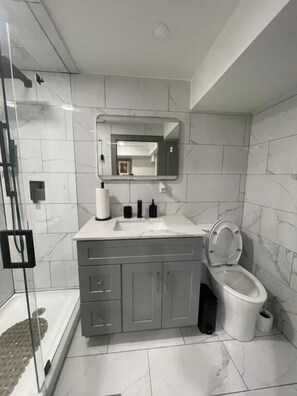 Un bagno con doccia, toilette, lavabo e specchio.