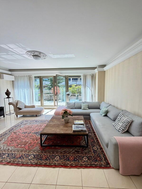 A living room with a sofa, a coffee table, and a large rug. - Luxurious 4BDR Avenue Malakoff Home - Arc de Triomphe (Paris)