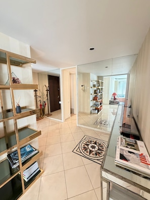 Un intérieur moderne avec une table basse en verre, un mur miroir et un sol carrelé.