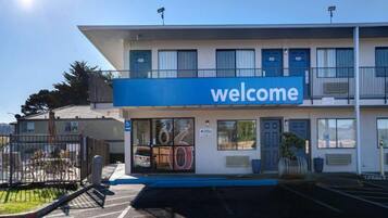 A building with a 'welcome' sign, a parking lot, and a gated entrance.