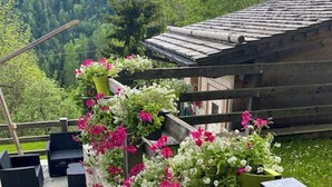 A stone staircase leading to a wooden deck with outdoor seating and flower planters. - Historic dwelling with terrace in Sauris (Sauris di Sopra)